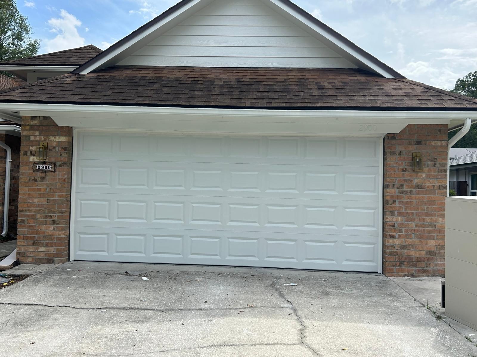 Classic white raised-panel double garage door on a brick home
