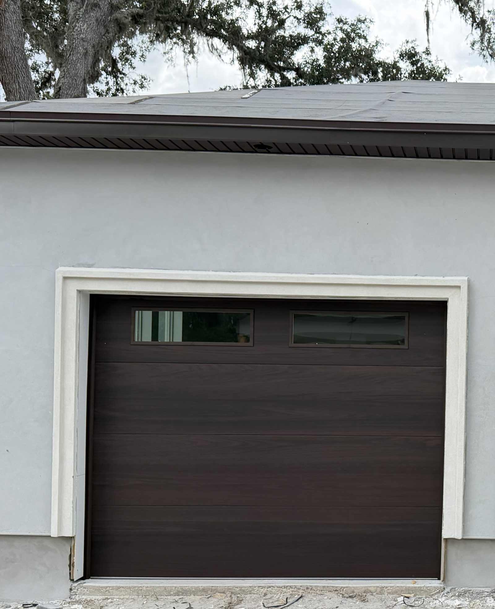 Wood-look garage doors with window inserts on new construction
