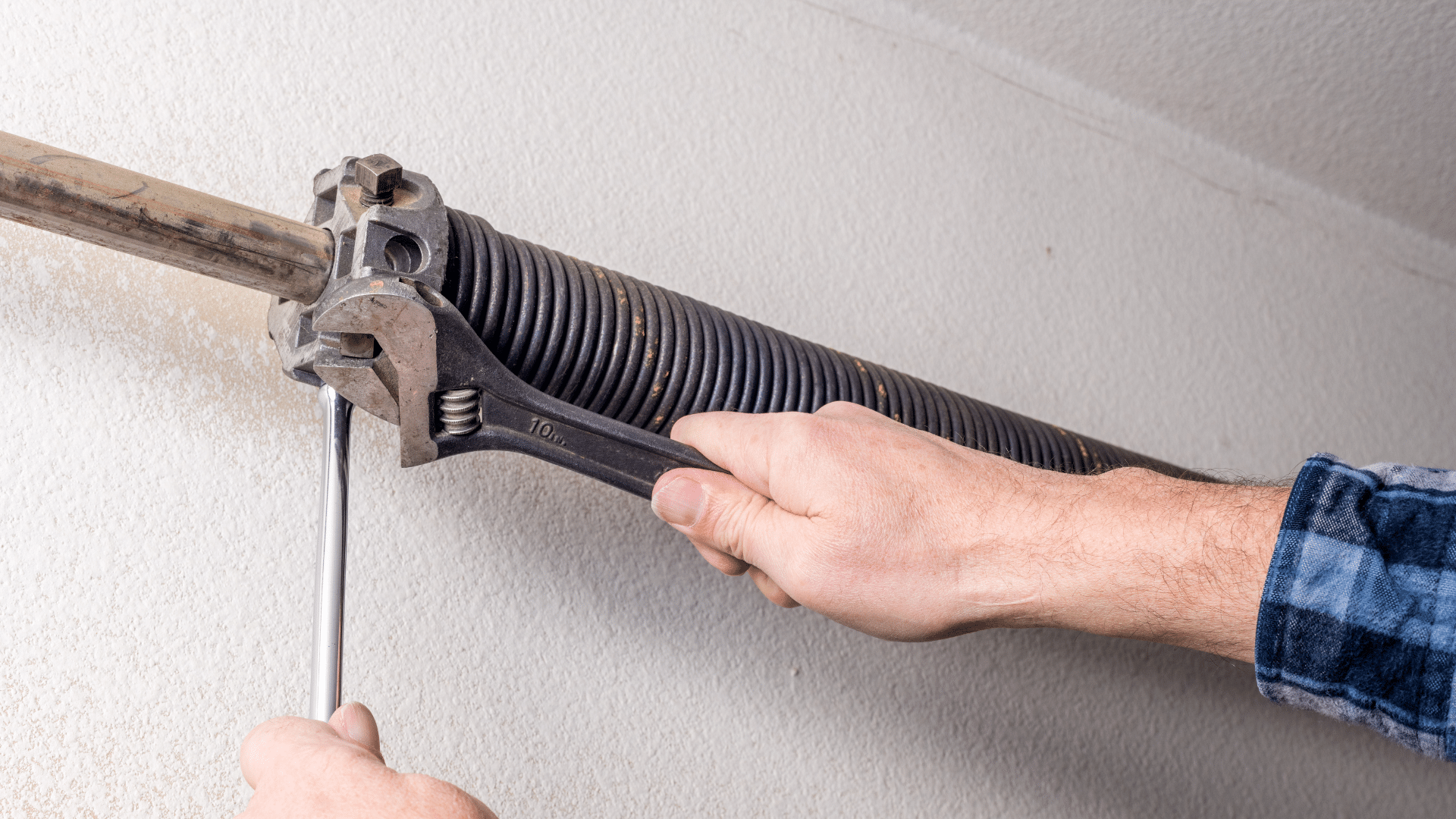 Technician using a wrench on a torsion spring when a garage door is heavy to lift