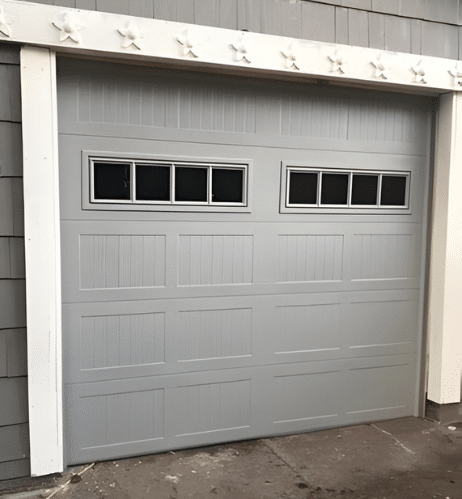 Technician lubricating garage door rollers during a maintenance tune-up